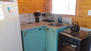 a kitchen with blue cabinets and a sink and a stove at Cabaña Las Abuelas in Xuí
