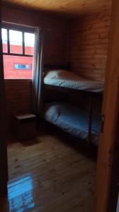 two bunk beds in a cabin with a window at Cabaña Las Abuelas in Xuí