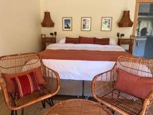 a bedroom with a bed and two wicker chairs at Uva Dulce B&B in Tunca Arriba
