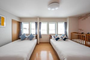 two beds in a room with two windows at Clematis in Nakafurano
