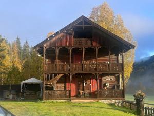 a large log cabin with a wrap around porch at Charming Guesthouse farm in Hølera