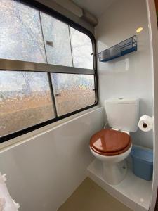 a bathroom with a toilet and a window at Sal da Terra Bus in Pirenópolis