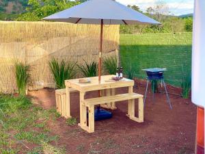 a picnic table with an umbrella and a stool at Sal da Terra Bus in Pirenópolis