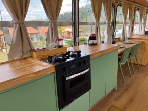 a kitchen with a stove and a counter with windows at Sal da Terra Bus in Pirenópolis