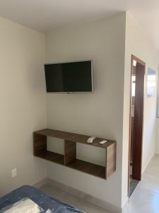 a living room with a tv on a wall at Pousada Netuno in Saquarema