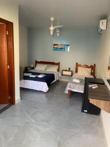 deux lits dans une chambre avec un sol carrelé dans l'établissement Pousada Netuno, à Saquarema 6 autres photos