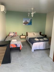 une chambre avec deux lits et un ventilateur de plafond dans l'établissement Pousada Netuno, à Saquarema