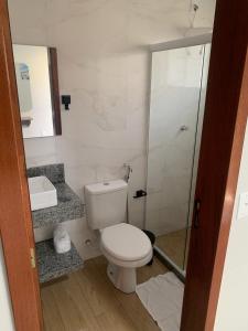 une salle de bains avec toilettes et douche en verre dans l'établissement Pousada Netuno, à Saquarema