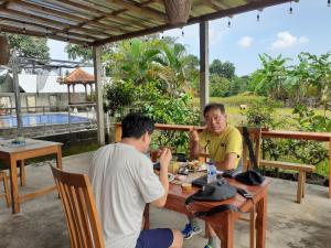 two men sitting at a table eating food at Griya Bun Sari in Sukawati