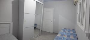 Dieses weiße Zimmer verfügt über einen Spiegel und einen Schrank. in der Unterkunft Casa Finger 800m do Centro e do Núcleo de casas Enxaimel anfitriões residem ao lado in Ivoti