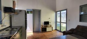 a kitchen and living room with a couch and a television at Chalé a Beira em Arroio do Sal in Arroio do Sal +12 photos