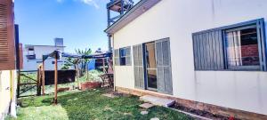 a white house with a window and a fence at Chalé a Beira em Arroio do Sal in Arroio do Sal