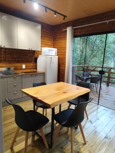 een keuken met een houten tafel en zwarte stoelen bij Cabana Penélope in Alfredo Wagner