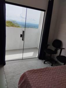 een slaapkamer met een grote glazen schuifdeur en een stoel bij Suíte 3 Centro São Thomé das Letras in São Thomé das Letras