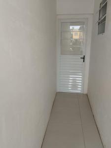 een witte kamer met een deur en een raam bij Suíte 3 Centro São Thomé das Letras in São Thomé das Letras