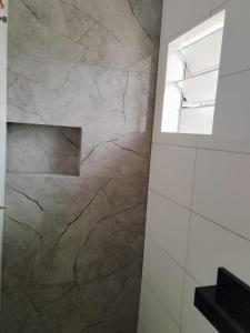 een badkamer met een grote marmeren muur bij Suíte 3 Centro São Thomé das Letras in São Thomé das Letras