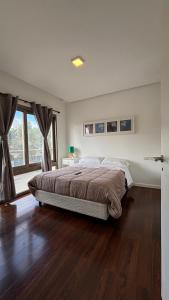 ein Schlafzimmer mit einem Bett und einem großen Fenster in der Unterkunft Costanera Sur Departamento in Río Gallegos