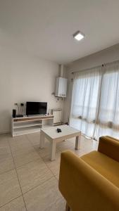 ein Wohnzimmer mit Fernseher, Couch und Tisch in der Unterkunft Costanera Sur Departamento in Río Gallegos