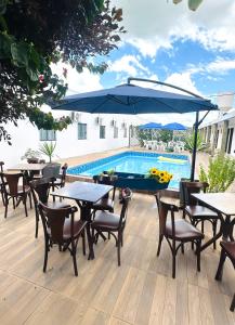 eine Terrasse mit Tischen und Stühlen und einem Pool in der Unterkunft Hotel Alexânia in Alexânia