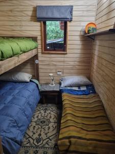 een kleine kamer met twee bedden en een raam bij Acojedora Cabaña en el Sur Panguipulli 