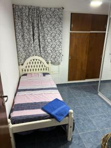 een klein bed in een kamer met een deur bij Cómodo in Santiago del Estero
