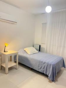 a bedroom with a bed and a table with a lamp at HABITACIÓN en VILLA ALLENDE, north green in Villa Allende