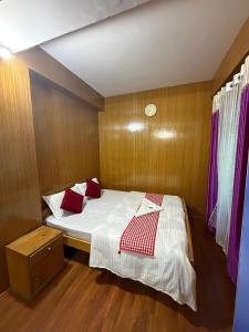 a small bedroom with a bed with red pillows at Mandrelling Inn in Tawang +1 photo