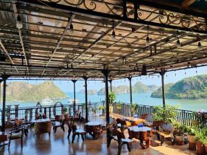 een restaurant met tafels en uitzicht op het water bij Sunrise Ocean Hotel & Rooftop Bar in Cat Ba