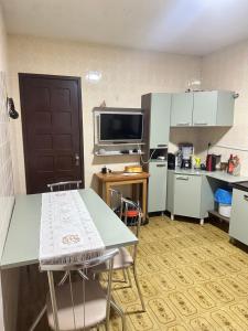 a kitchen with a table and chairs and a television at pousada cardoso - casa 2 in São Gabriel