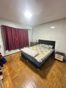 a bedroom with a bed and a red curtain at pousada cardoso - casa 2 in São Gabriel +3 photos