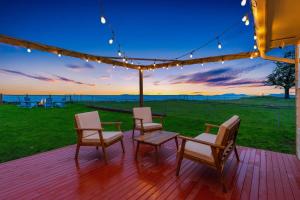 drie stoelen en een tafel op een terras met uitzicht op de zonsondergang bij Marbella Lane Wave HS w EV Charger Oceanfront in San de Fuca