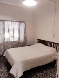 een slaapkamer met een wit bed en een raam bij Vm casa in Villa María