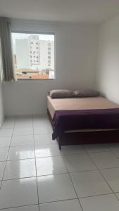 een slaapkamer met een bed en een raam bij Apartamento 3 Quartos Praça Cel Tibúrcio Barra in Muriaé