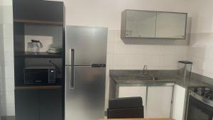 een keuken met een roestvrijstalen koelkast en een magnetron bij Apartamento 3 Quartos Praça Cel Tibúrcio Barra in Muriaé +26 foto's