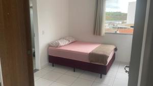 een klein bed in een kamer met een raam bij Apartamento 3 Quartos Praça Cel Tibúrcio Barra in Muriaé