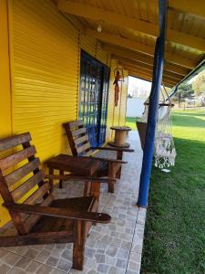 un porche avec deux chaises en bois et une balançoire dans l'établissement Sossego na Serra Catarinense - Casa em Lages, à Lages