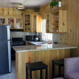 een keuken met houten kasten en een zwarte koelkast bij Villa Monte Alba in San Felipe de Puerto Plata