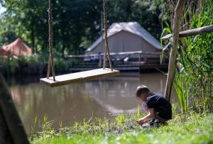 a boy sitting in the grass next to a swing at KARIBU - Olifant in Kasterlee +24 photos