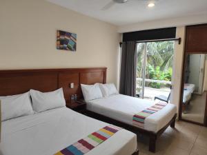 a hotel room with two beds and a window at 7mo Color Hotel Boutique in Mahahual