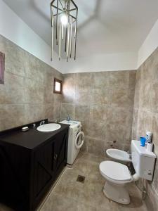 een badkamer met een wastafel, een toilet en een kroonluchter bij La Calandria in Cerrillos