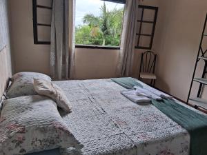 een slaapkamer met een bed met een raam en een stoel bij Recanto verde in Ilhabela