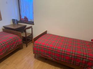 een kamer met twee bedden, een tafel en een bureau bij Casa Cappuccetto in Imer