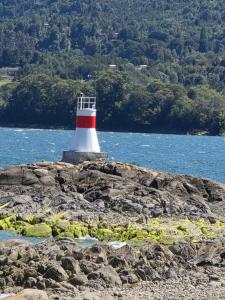 a lighthouse on a rocky island in the water at Cabañas cochamó in Cochamó
