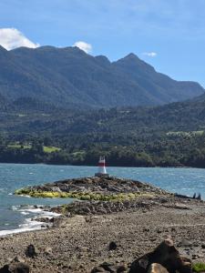 a lighthouse on a rocky island in a body of water at Cabañas cochamó in Cochamó