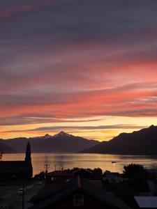 a sunset over a body of water with mountains at Cabañas cochamó in Cochamó