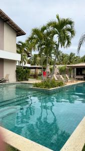 ein Swimmingpool in einem Resort mit Palmen in der Unterkunft Guarajuba Flat Acqua 103 in Camassari