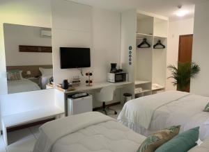 a bedroom with two beds and a desk with a tv at Iloa Studio Alagoas sofisticação de alto padrão in Barra de São Miguel +34 photos