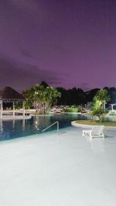 a white chair sitting in the middle of a swimming pool at Iloa Studio Alagoas sofisticação de alto padrão in Barra de São Miguel