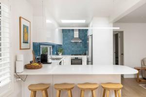 a kitchen with a white counter and wooden stools at Verona in Shoal Bay