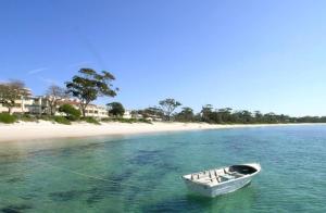 a boat in the water next to a beach at Verona in Shoal Bay